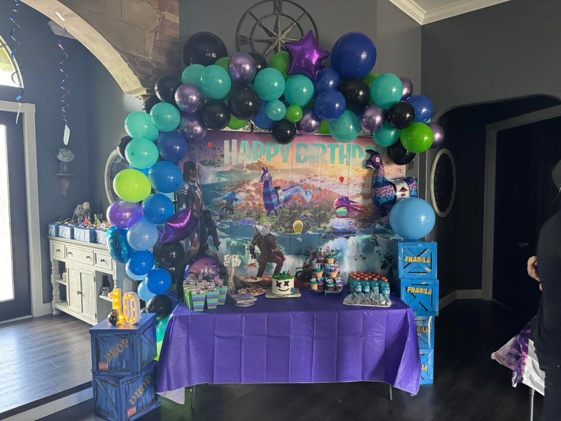 Fortnite themed balloon arch above a dessert table