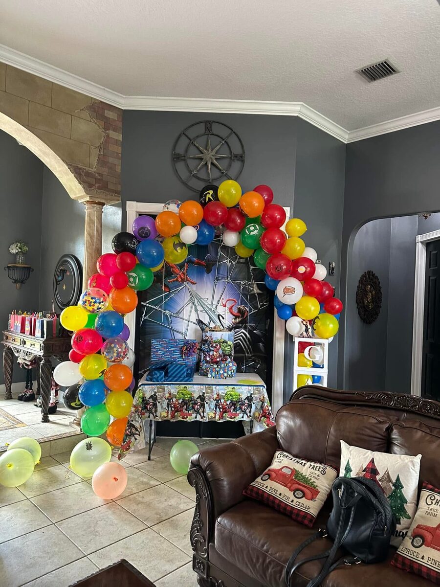 Superhero themed balloon arch above a gift table